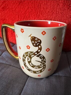 Gold-Handled Cream Ceramic Mug with Red Interior and Floral Snake Design